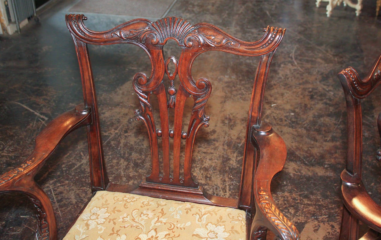 Marvelous pair of exceptionally carved English Chippendale armchairs with pierced back splat and serpentine crest rail.  Having out-swept arms with detailed carvings, and resting on cabriole legs terminating in claw feet.  Exhibiting a beautiful