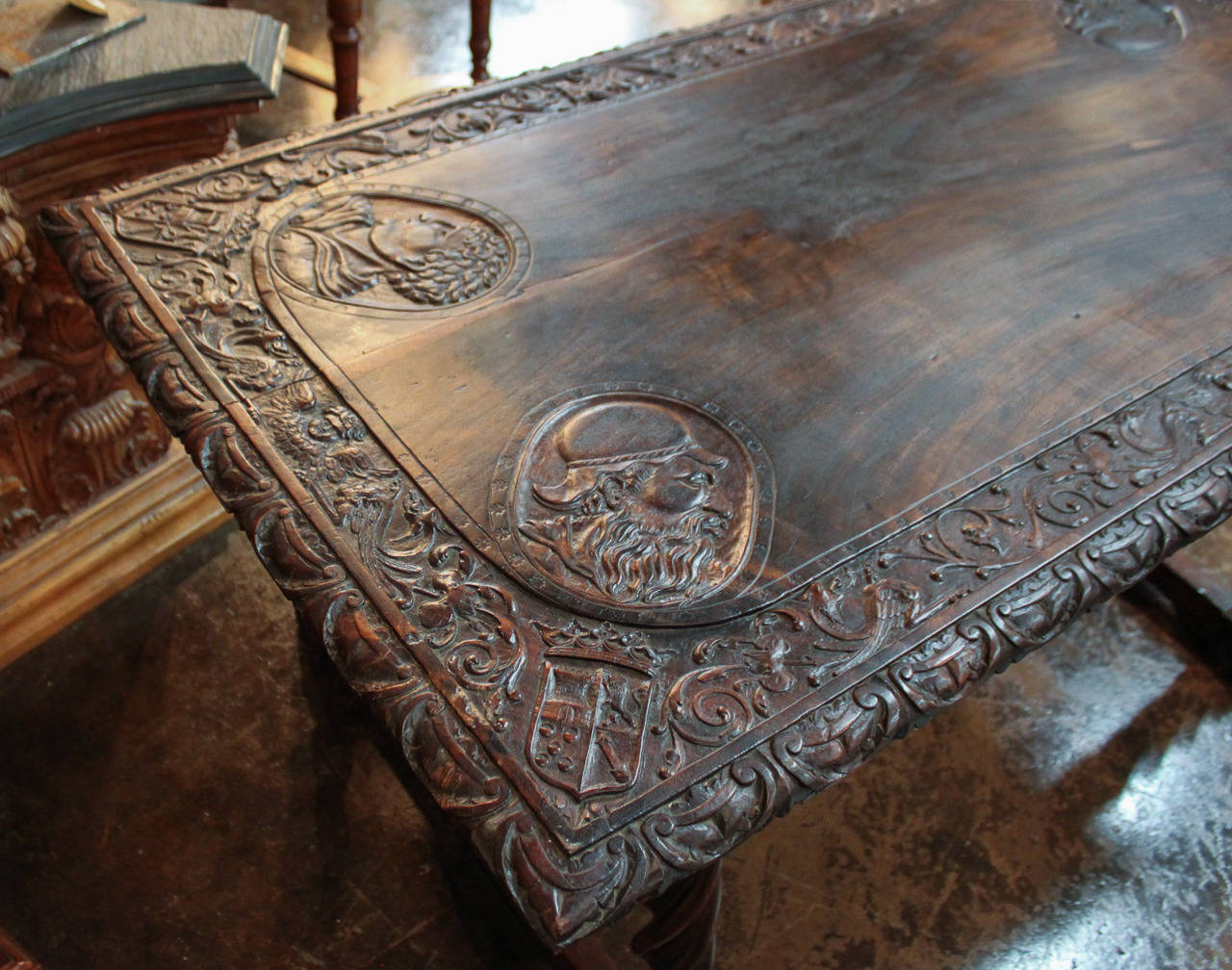 Superbly hand carved Italian walnut trestle table resting on twisting legs. Having wonderfully carved faces in tabletop, crest and shield in each corner, adorned in foliate and winged putti motif, and the time worn patina offers rich character and