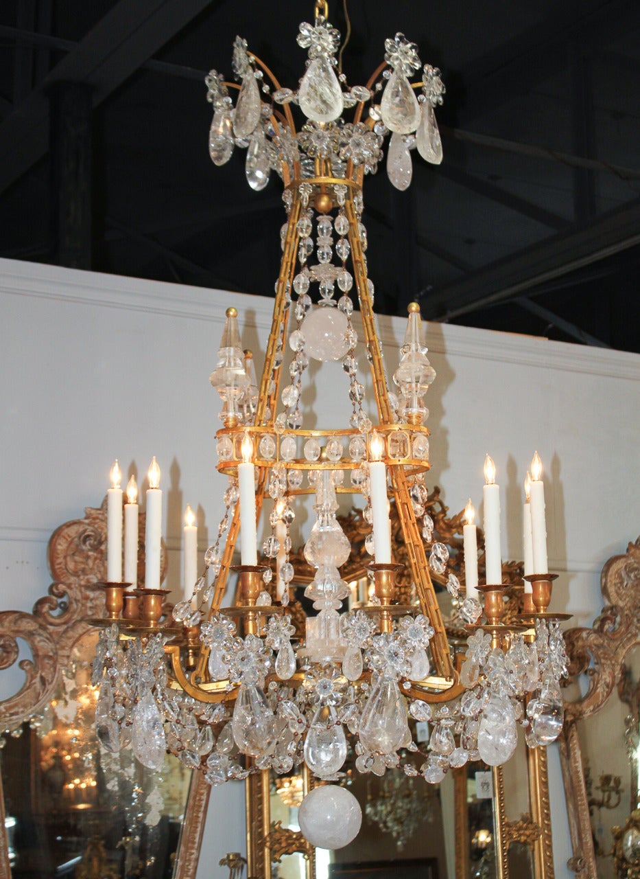 Extremely rare and magnificent true 19th century French gilt bronze and rock crystal twelve-light chandelier. Having an elegant bronze frame punctuated with impressive obelisks and connected by heavy beaded chains. Exhibiting large drop prisms and