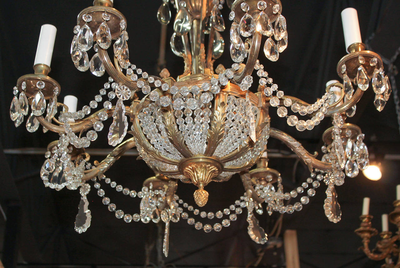 Magnificent French heavy cast gilt bronze and crystal 8-light chandelier. Having large beaded strands connecting each gracefully curved arm, large drop prisms overall, and bronze frame adorned in acanthus leaf motif.  A stunning piece for numerous