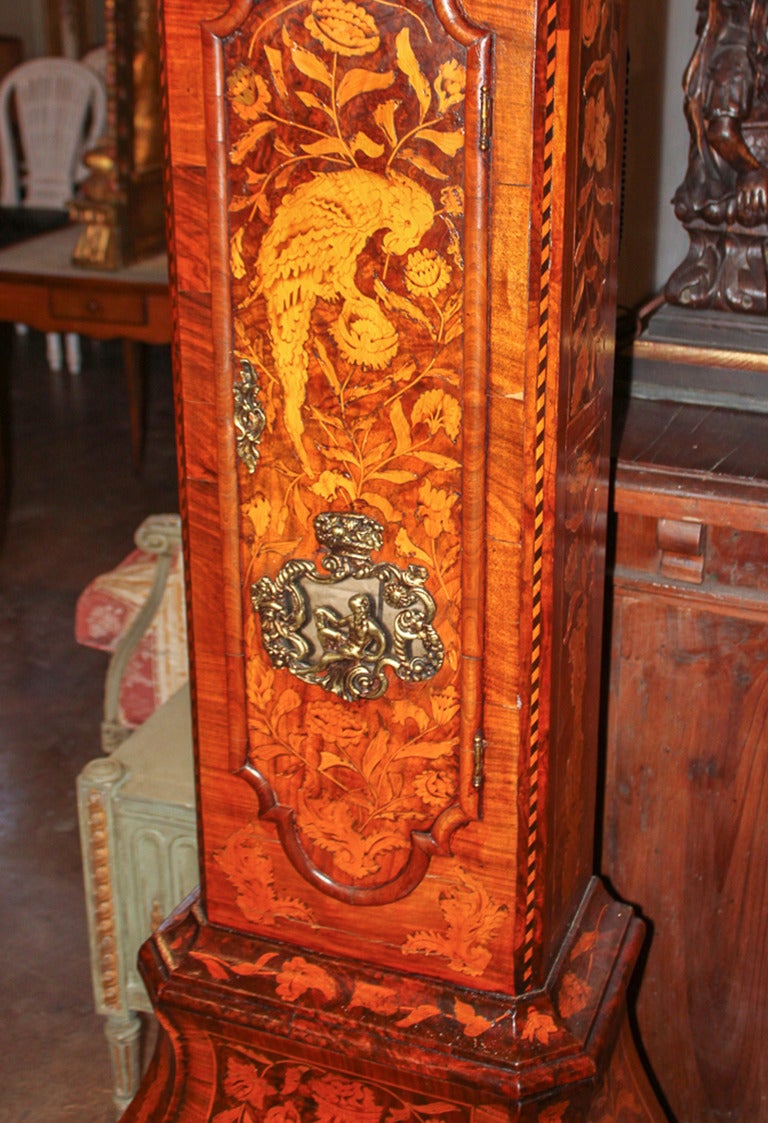 Magnificent early 19th c. Dutch marquetry inlaid long case clock.  Profusely inlaid with floral leaf, urn, and bird motifs.  Having bombe shaped lower section resting on bunn feet and with cast bronze figural adornment of Father Time in door. 