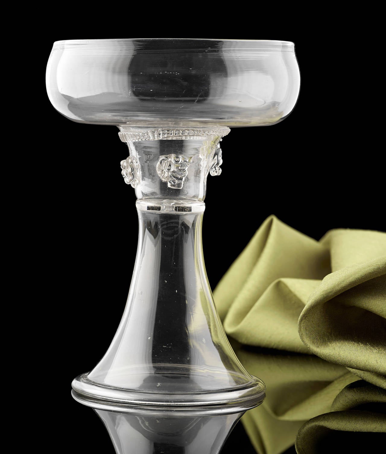 A Facon de Venise Clear Glass Roemer, Approximately 7 inches in height; Dutch 1690; it has a flattened hollow bowl and four applies prunts around the stem, and stands on a tall trumpet foot.