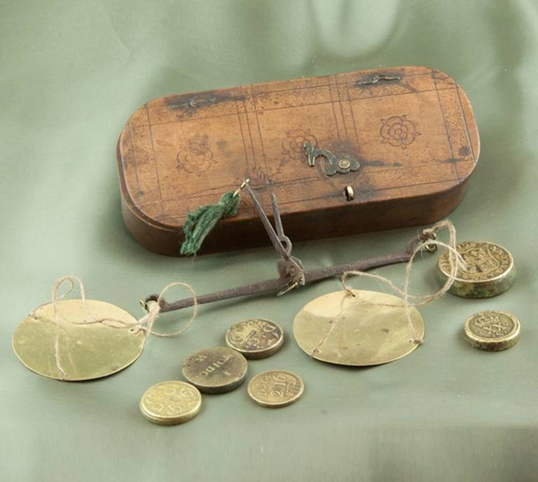 A rare set of 17th Century merchant's coin scales and weights in their tailor-made box decorated with three Tudor roses and a stippled border.

The box is approximately 5 inches in length; the hand held scales are steel with two little brass pans.