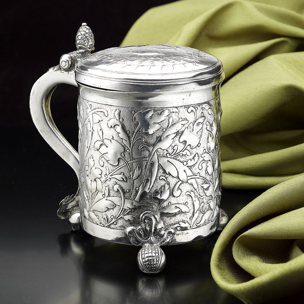 A Scandinavian Silver Tankard, Norwegian or Danish, maker’s mark only I intersecting S, perhaps Johan Schluter of Bergen, c.1650 on three pomegranate feet, chased with scroll foliage on a matted ground, the lid with contemporary accolle arms,