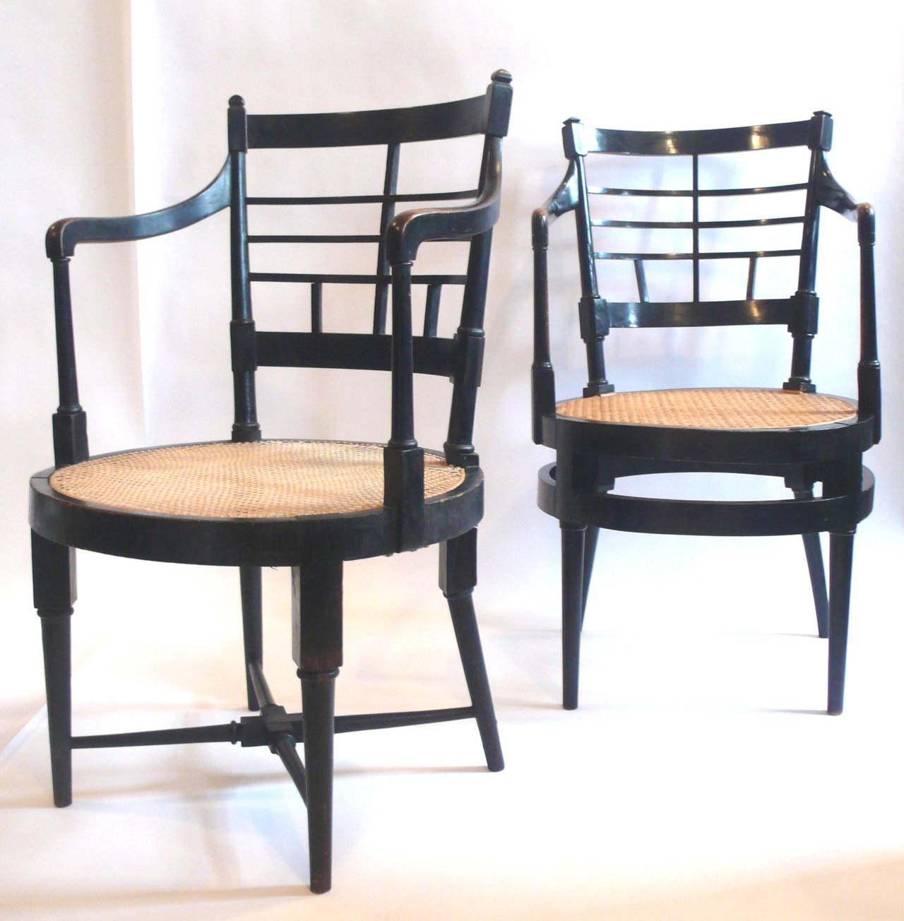 A stunning mismatched pair of ebonized armchairs by Edward William Godwin. 
Probably manufactured by William Watt, circa 1867-1885.
Newly caned seats, original ebony finish. 

Reference: The Secular Furniture of E. W. Godwin by Susan Weber