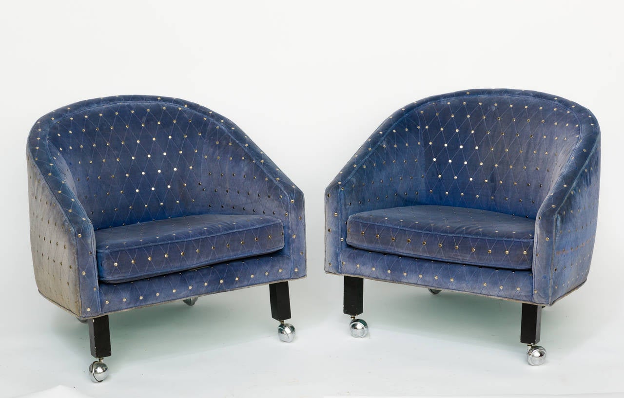 Pair of Kipp Stewart style lounge chairs. They have casters on all the legs and have a studded upholstery.