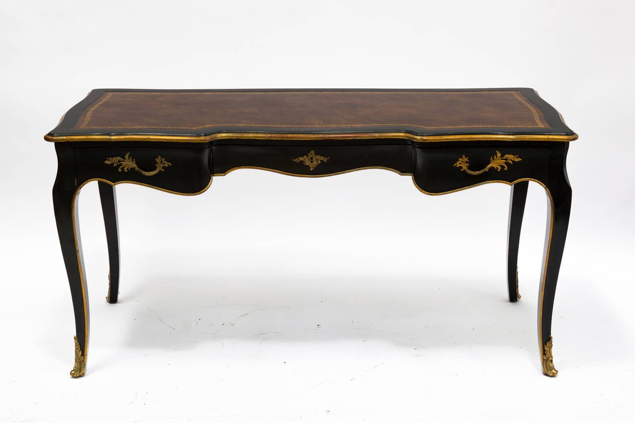 A Louis XV painted desk with brass ormolu hardware and mounts. Writing sides at each end. Brown leather top with tooled end gilt border.