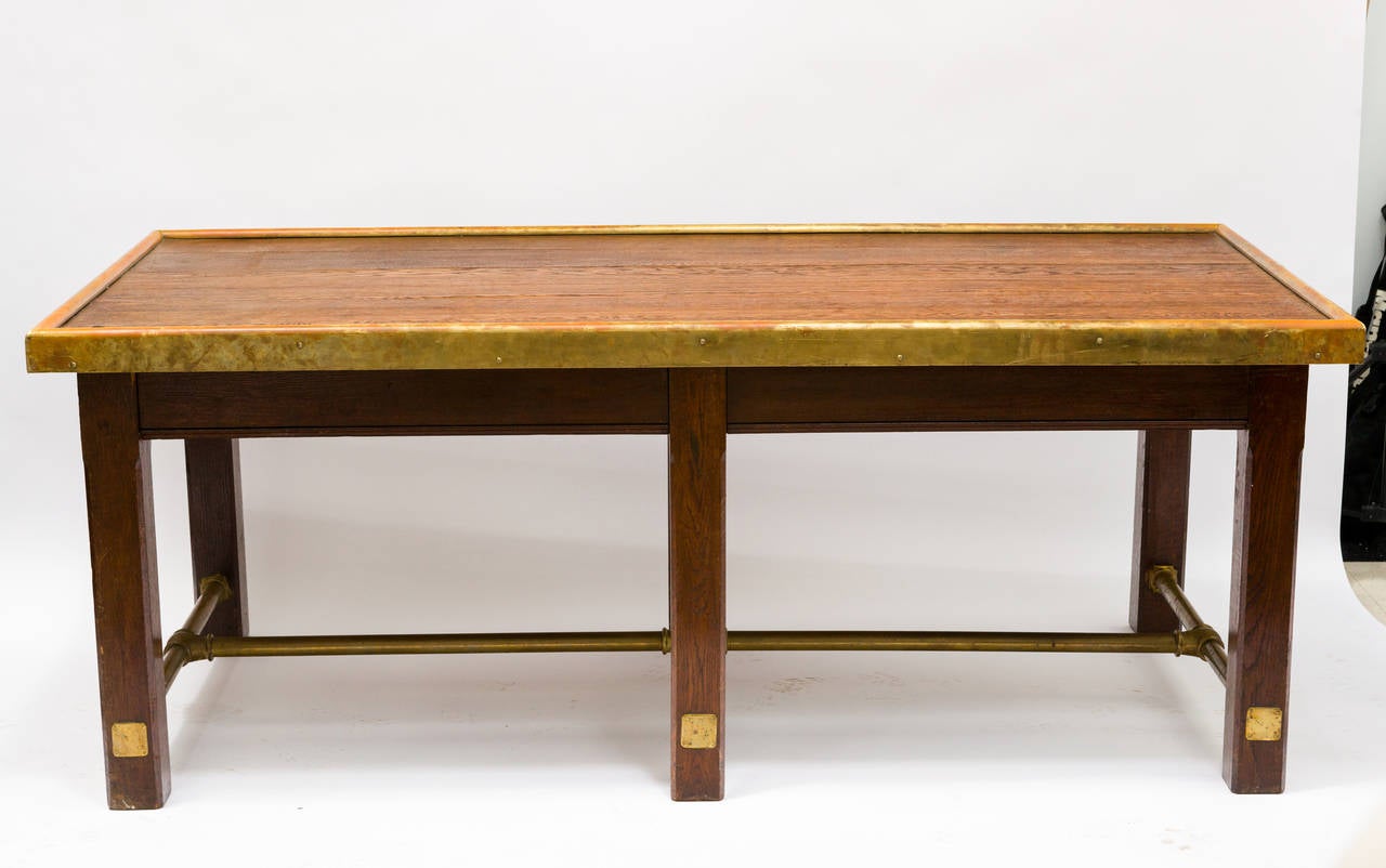 An impressive library or dining table with brass stretcher and brass molding. English, from the 40's.