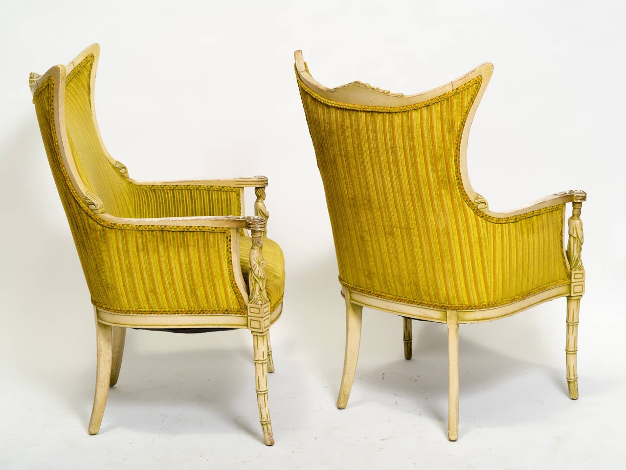 Pair of 1950s James Mont style Asian lounge chairs. They have faux bamboo legs, a carved temple shaped top backrest and figures on the arm fronts.