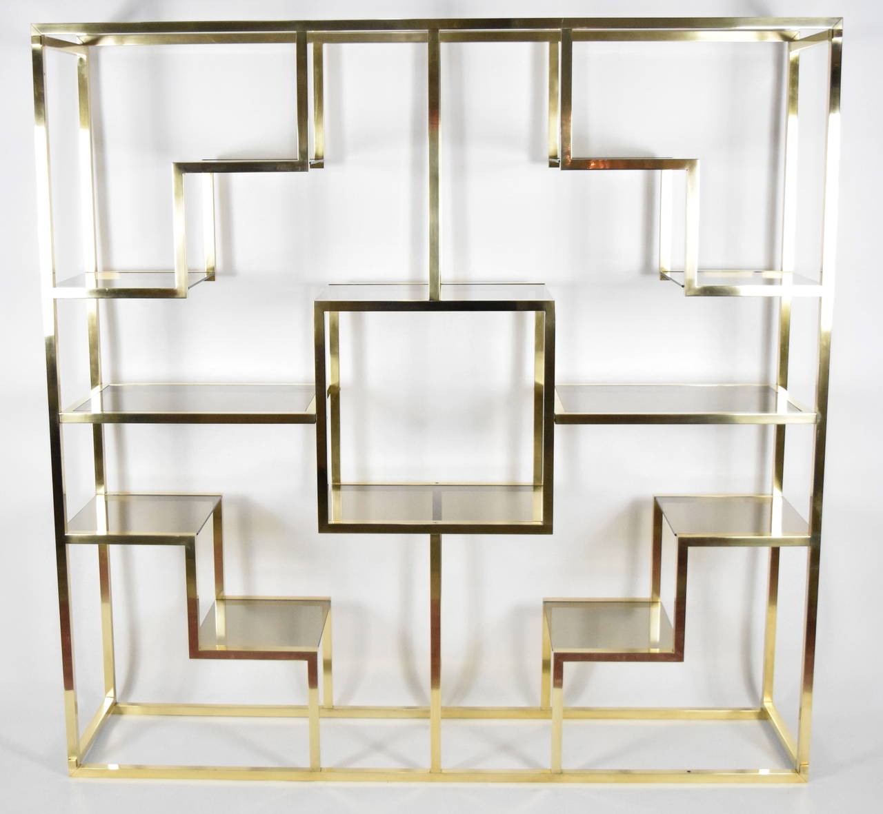 This is a beautiful étagère by Romeo Rega. It is solid brass with all new smoked glass shelves. Very beautiful.