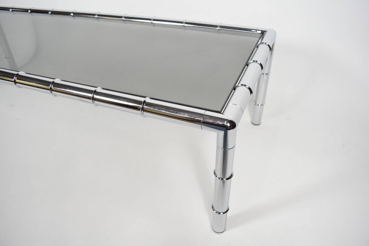 This is an Adrian Pearsall coffee table with a chrome frame in faux bamboo. The glass is slightly smoked. The table was part of a set and used with a sofa….see our listings for a picture of the sofa.