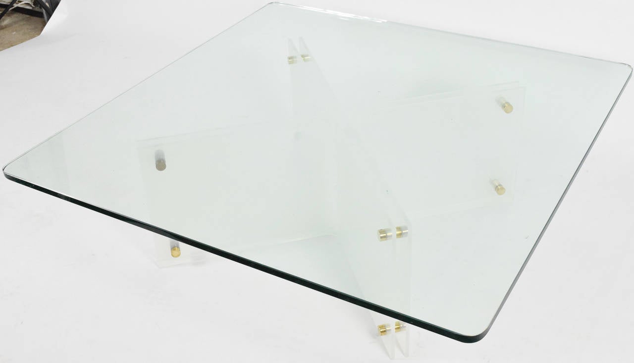 This is a gorgeous Lucite and glass with brass rivets coffee table by Neal Small. The glass is excellent and 3/4