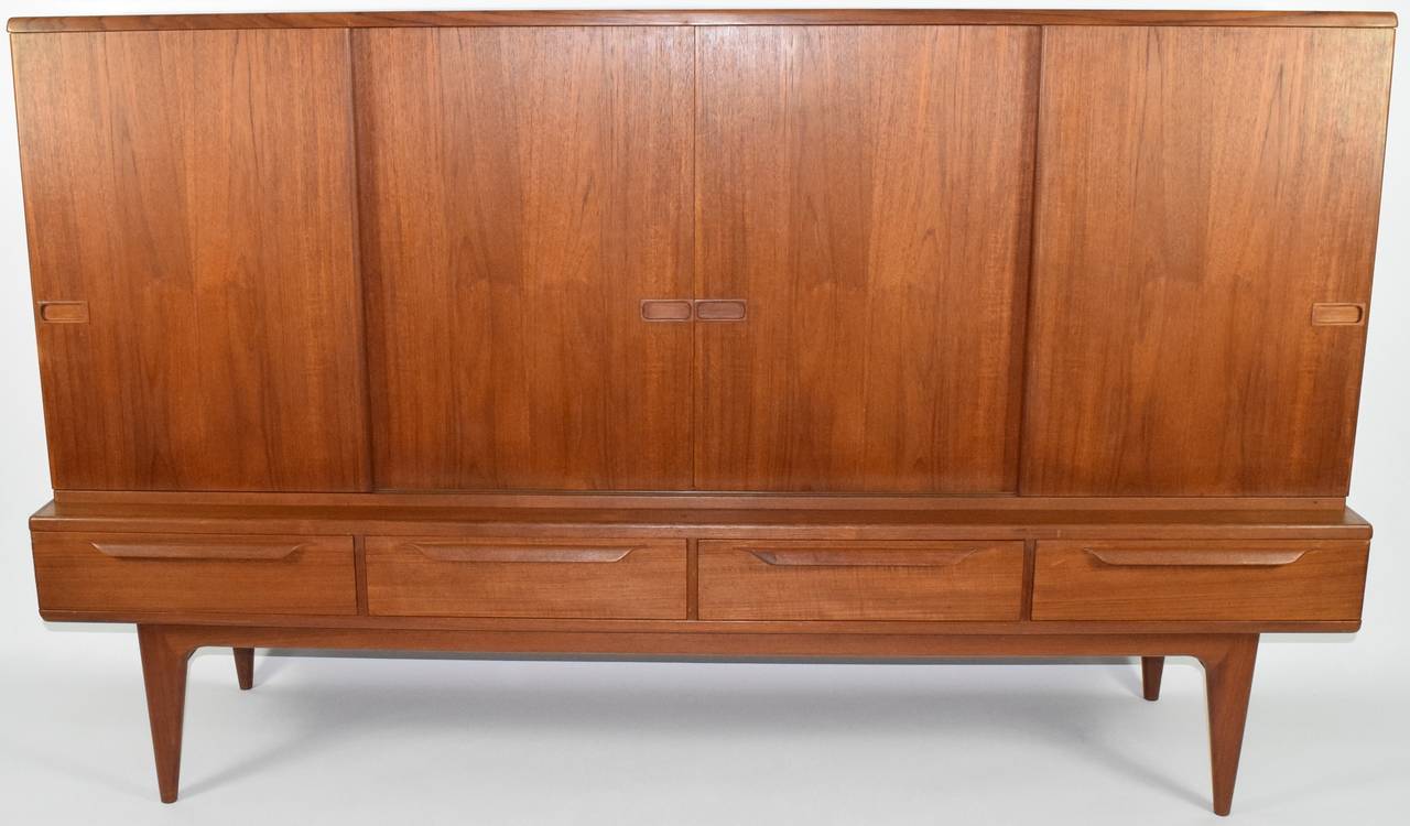 Very beautiful teak sideboard, circa 1950s, four sliding doors open to shelving and four lower drawers. This piece is very well made in construction. Edges are beveled, handles are formed wood, beautiful finish.