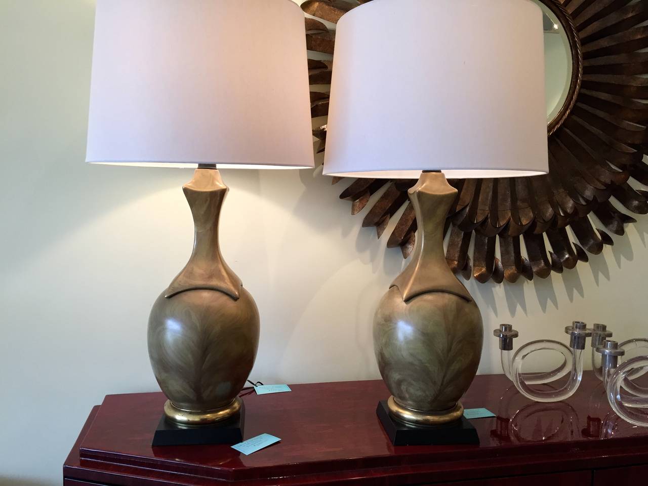 These important lamps are beautifully executed with a handsome and interesting glaze. They are ceramic, and mounted on a black wooden base accented by a band of brass.

They measure 28