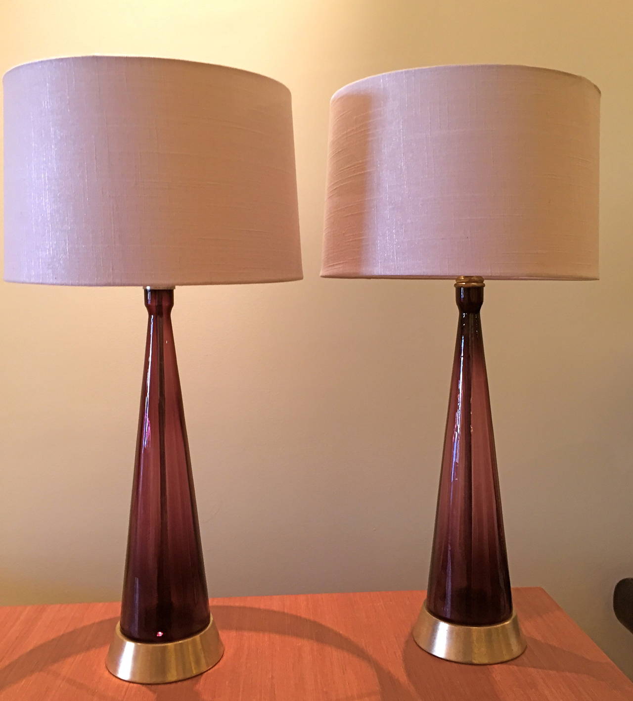 Blenko Glass was unsurpassed for its clarity of coloration and its strikingly simple shapes.  This pair of amethyst glass lamps are 23.5 inches to the top of the finial.  The glass itself plus the base is 20 inches tall.  The lamp shades are  not