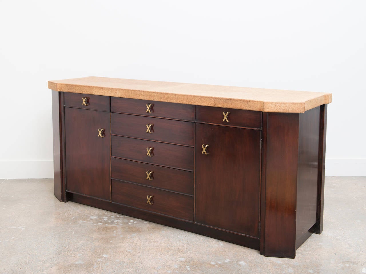 Highly stylized credenza or cabinet designed by Paul Frankl.  This cabinet exemplifies Frankl's fine Mid Century design detailing elegant hardware combining materials such as cork and mahogany with brass accents.