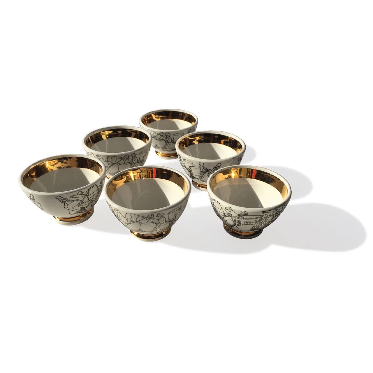 Set of six Fornasetti cocktail snack bowls with black and white graphics with gilt interior and bottom pedestal. Bowls read: 
