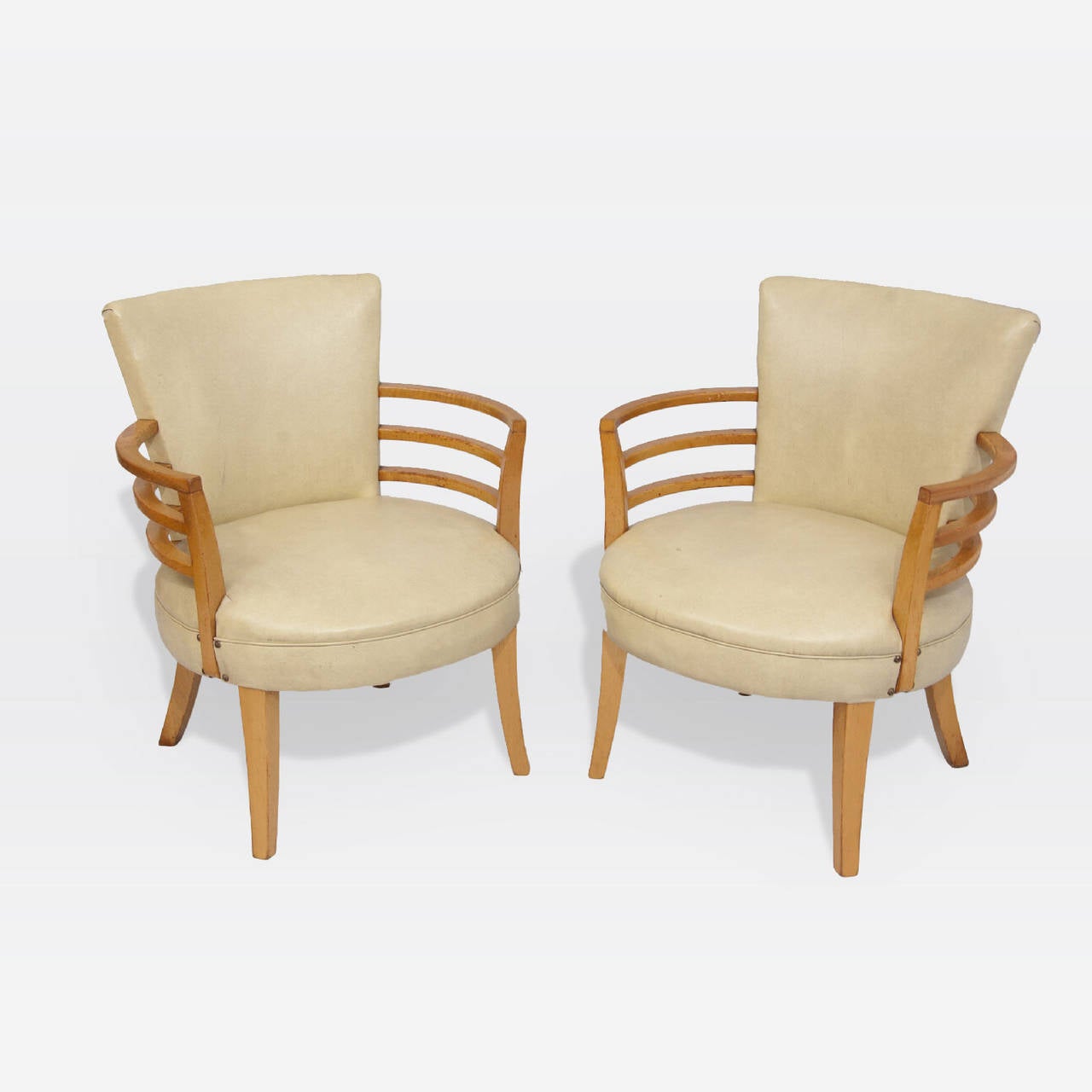 Curved seat backs and round seats in buff vinyl. Blonde wood curved arms and tapered legs.