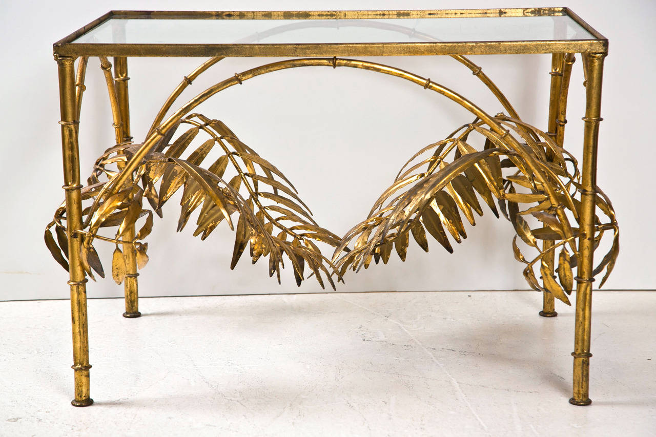 Gilt metal cocktail table in the form of bamboo and palm leaf with inset glass top. Possibly German or Italian, Mid-20th century.

Note: (not pictured) glass top has been replaced with a 1/2" thick glass to fill the lip.