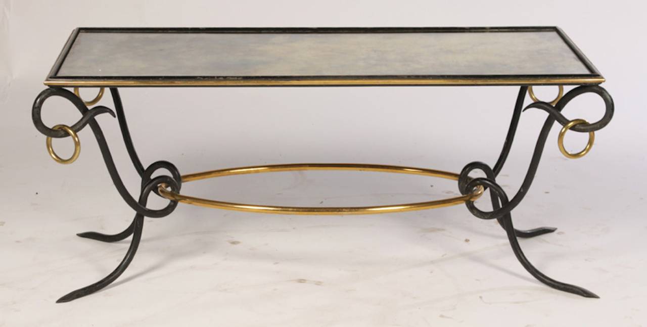 A rare and exquisite iron and bronze mirrored top coffee table designed by René Drouet, circa 1940. The original mottled mirrored top supported by twisted iron supports connected by a bronze oval stretcher. 

Dimensions: Height 20