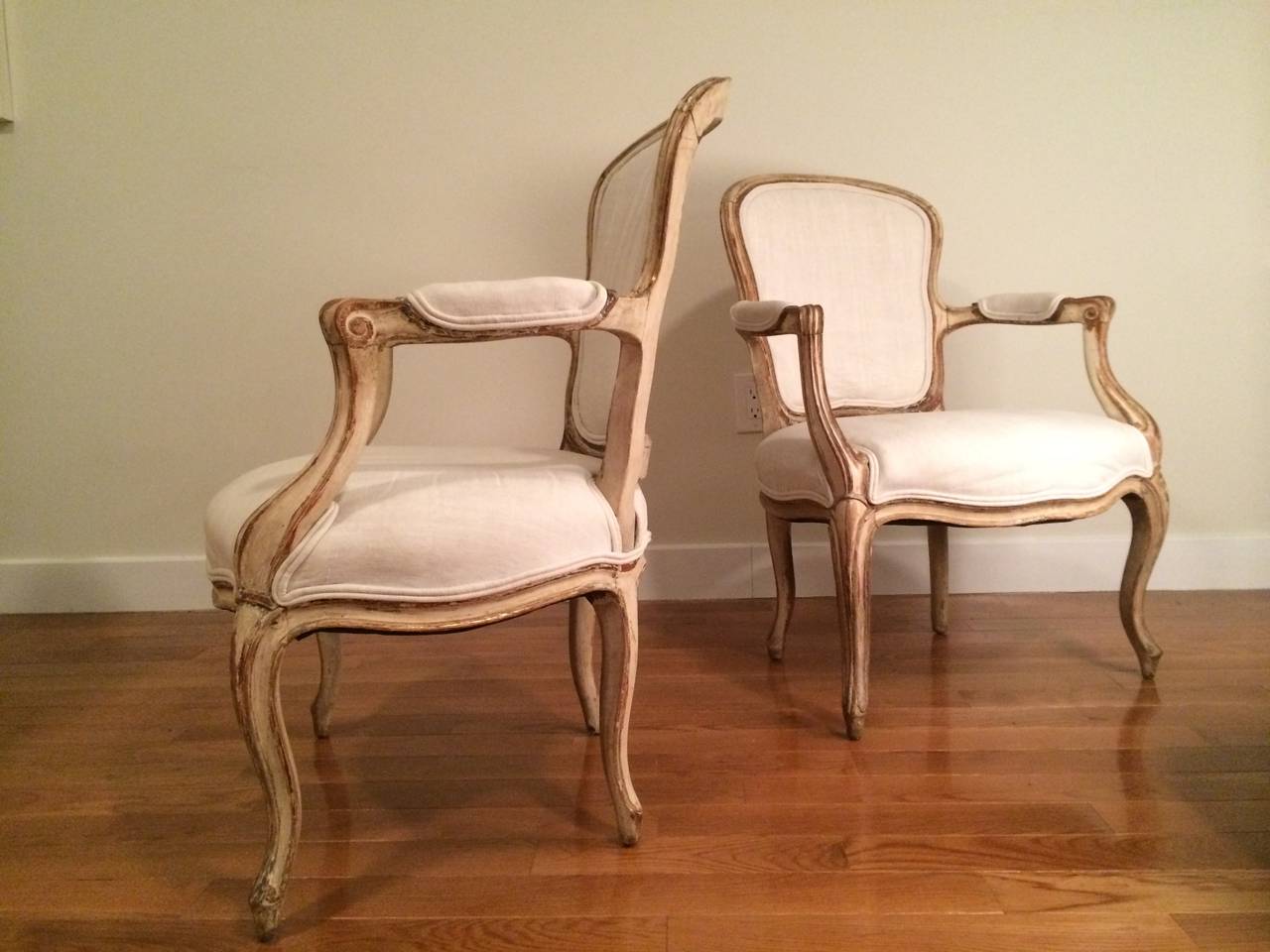 A pair of French Louis XV style fauteuils in their original finish (paint with gilt detail), now distressed.