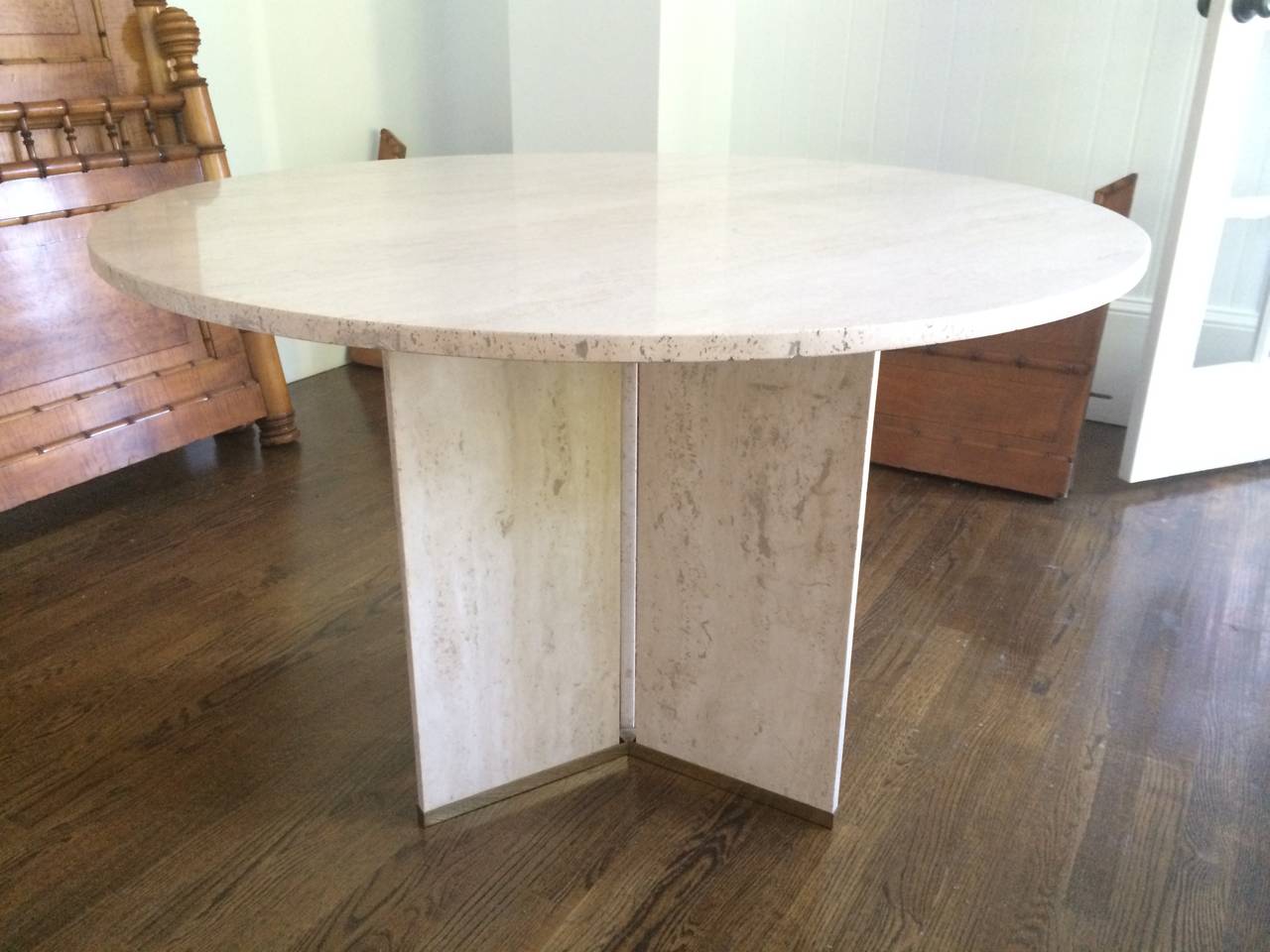 A unique travertine center or dining table. Round top placed on three panels (corolla form) encased in brass, Europe, 1970s.

Maker unknown in the spirit of Gabriella Crespi.
   