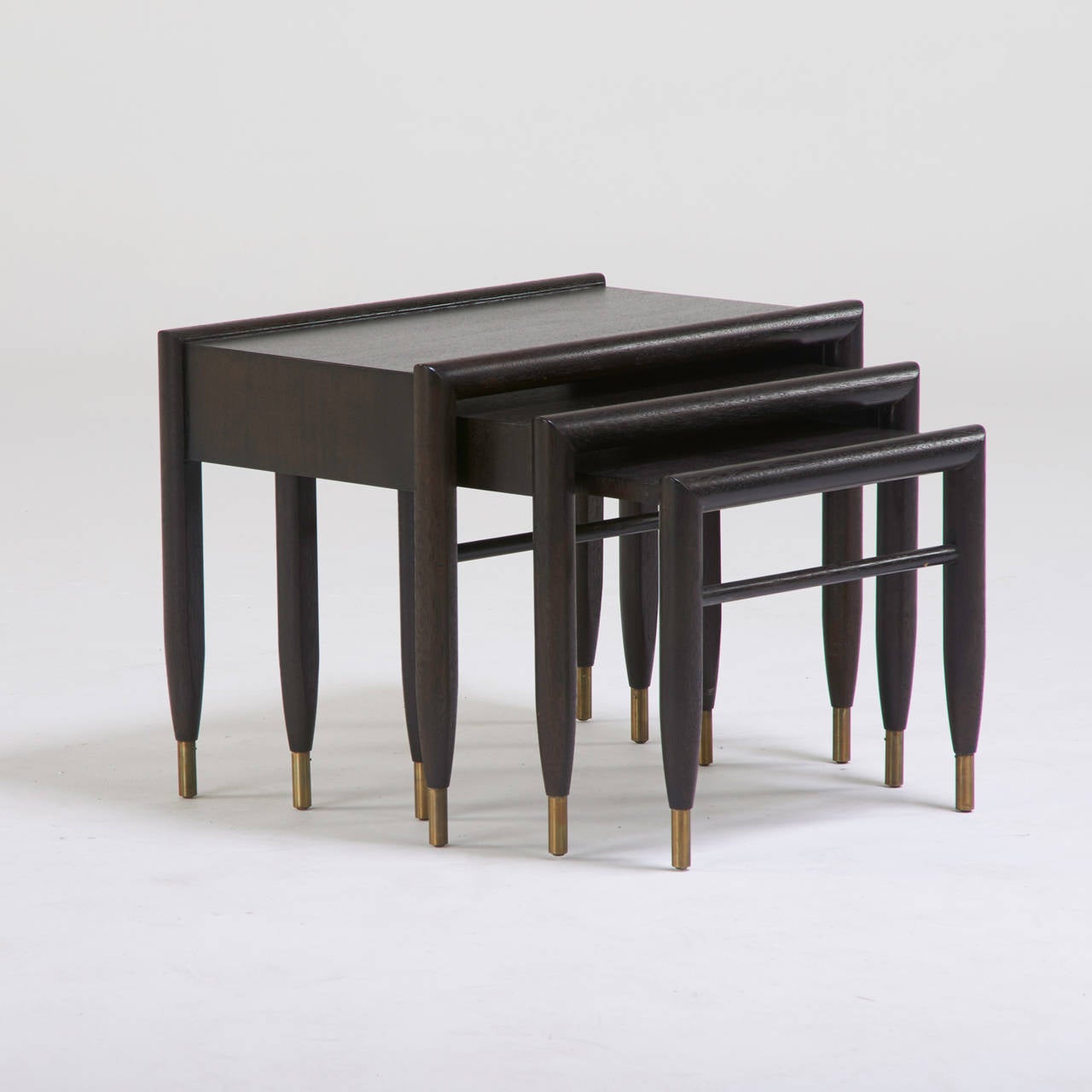 John Keal, three nesting tables, California, 1950s, stained and lacquered mahogany, brass, decal labels. Dimensions: Largest 19.5" x 25.5" x 16".