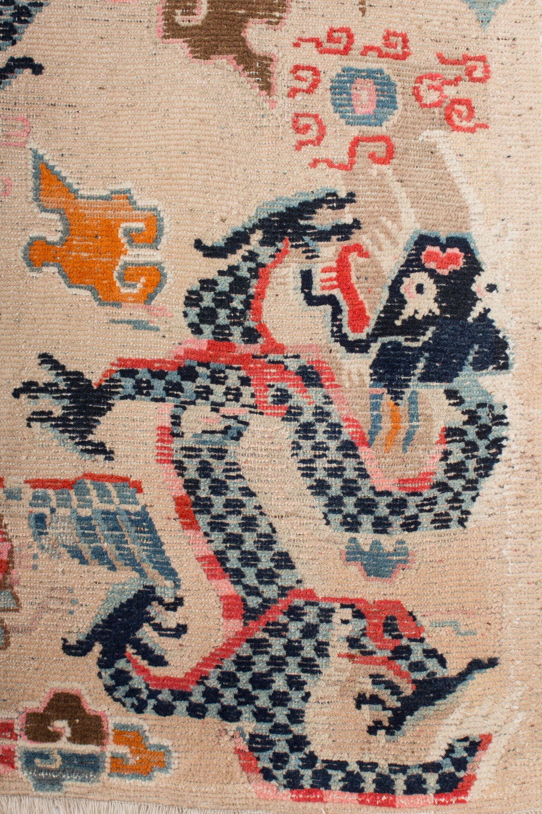 This ivory ground Tibetan Khaden sitting and sleeping Rug depicts two Phoenix beside the two dragons playing with the fire pearl. 

The powerful dragons are exquisitely drawn with a scaled bodies and fierce facial expressions.  They almost appear