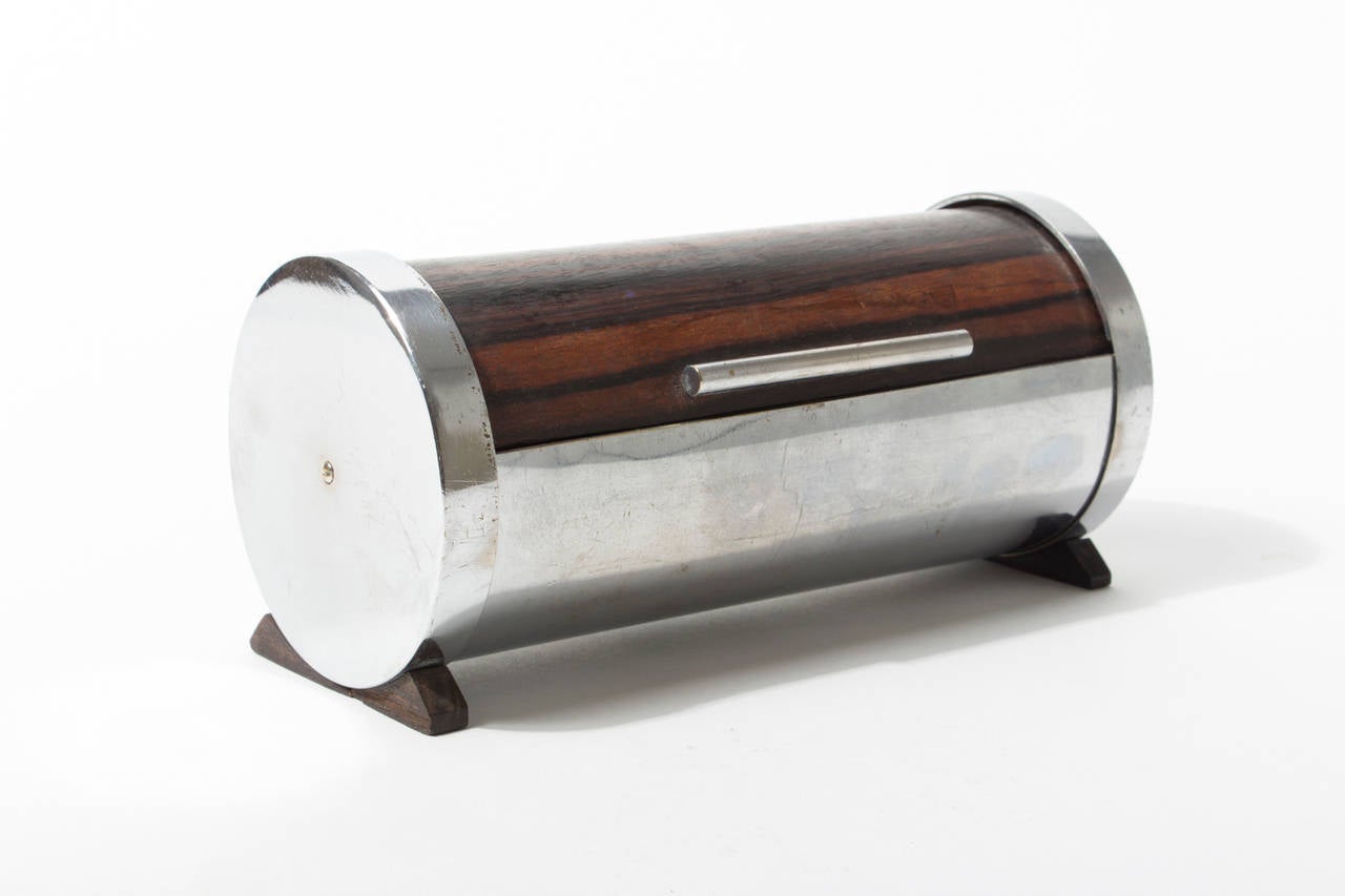 This cylindrical box is a rare example of the early works by the workshop from the 1930s. The structural design of the box (screw mounted sides), the experimental use of the bended wood for the lid and the use of nickel plated brass make it a true