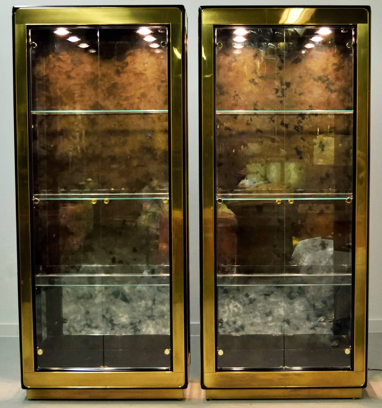Both cabinets have recessed lighting. Antiqued mirror back panel detail with adjustable glass shelves. Glass front doors and glass side cabinet detail.