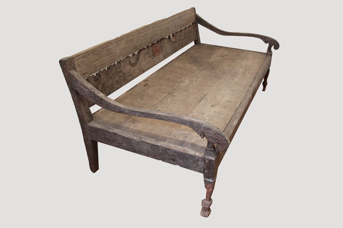 Colonial influenced antique daybed. Hand carved and made from natural aged teak with original paint. Includes white cotton mattress and pillows. Comfortable design for sleeping or relaxing. Each length of the arm is carved from a single piece of