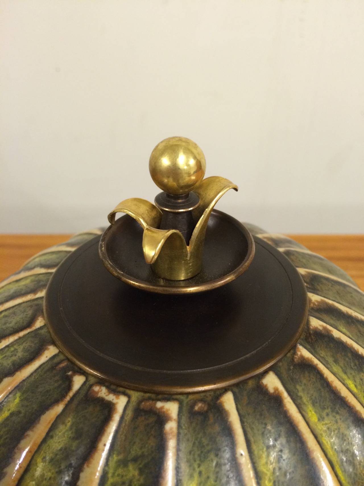 Arno Malinowski stoneware lidded jar with vertical, fluted pattern. Decorated with solfatara glaze. Signed monogram, 20315. Made by Royal Copenhagen. Lid and base of patinated and partly gilded bronze. Lid stamped monogram KA for Knud Andersen.