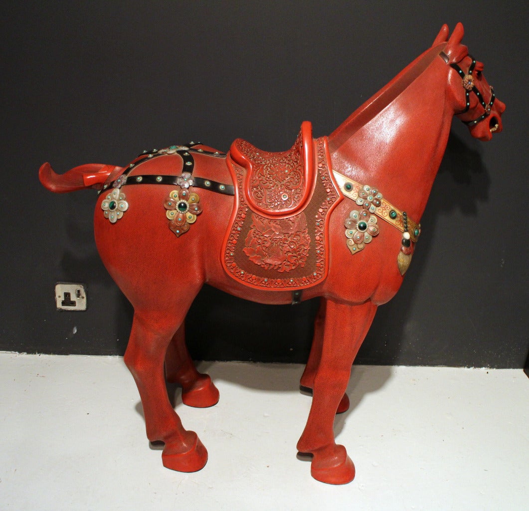 A very large Chinese red lacquer horse with carved saddle and applied stone bridle and tack, the horse is very finely carved and has a very expressive face.

