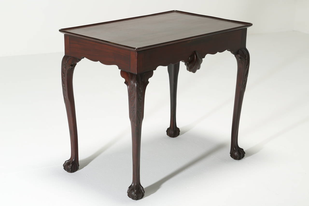 An elegant Irish George III Mahogany silver table of excellent size with dished top, carved shell mask frieze, cabriole leg terminating in claw and ball feet. The table has a shell motif,scrolled apron and acanthus leaf carving to the top of the leg.