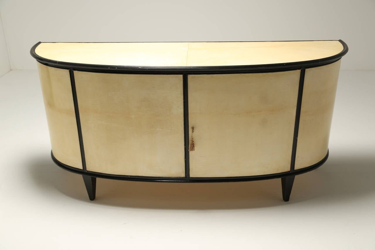 An Italian parchment covered and ebonised demi-lune 2 door sideboard with 10 internal drawers. A very elegant sideboard enclosing two banks of 5 drawers.