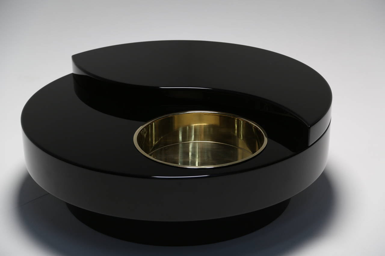 A Black Gloss Mario Sabot revolving coffee table with circular brass bucket. Gloss black table in near perfect condition, heavy and well made and swivels very nicely. The brass bucket is meant to hold your assorted drinks bottles. This is a 1970s