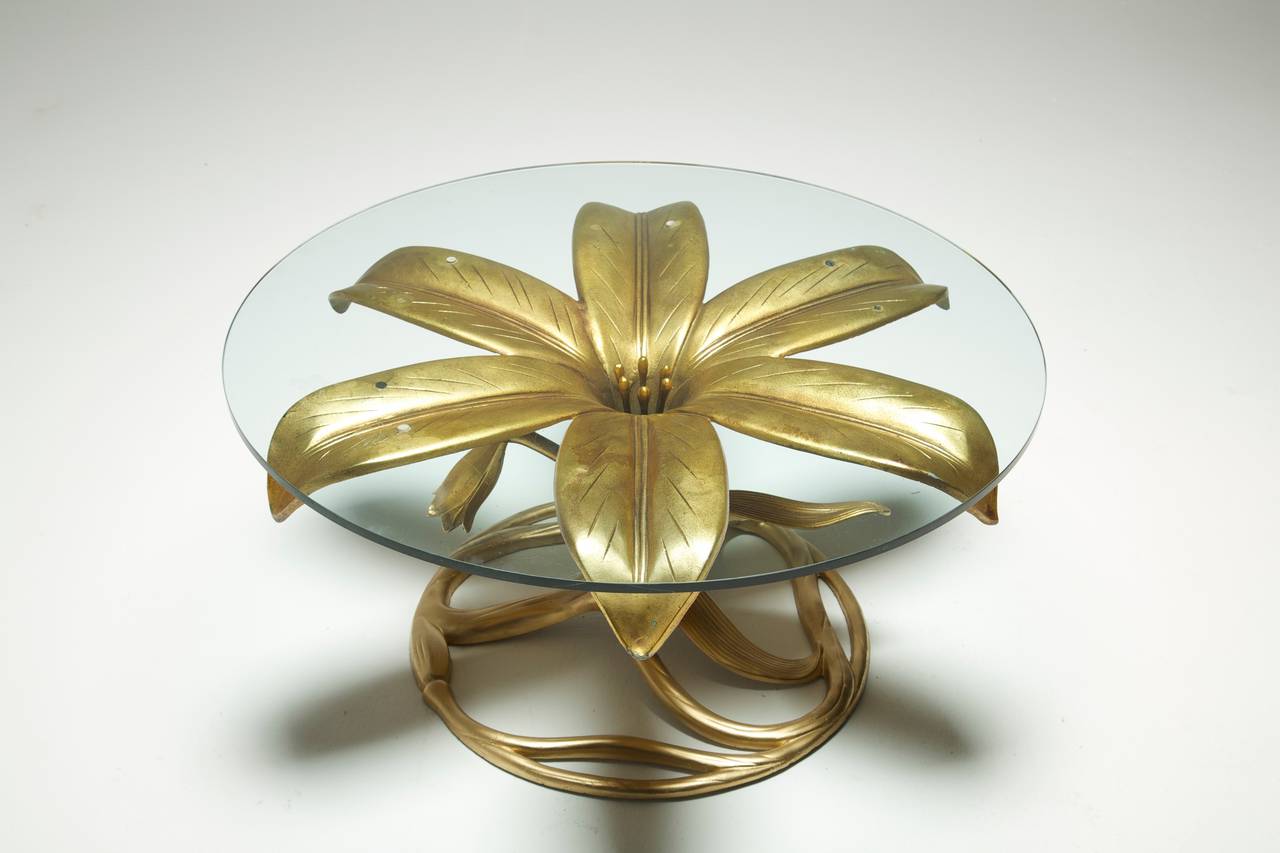 A gilt metal coffee table by Arthur Court in the style of a lily. The table base is in really good original condition, its made from a lightweight metal in the form of a large open Lily. Comes with original glass top. Easily shipped worldwide.