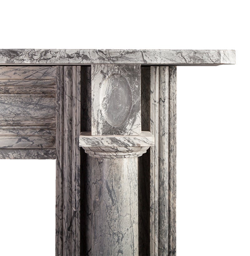 Ein Kamin aus grauem Bardiglio-Marmor aus der späten georgianischen Zeit.

Die freistehenden dorischen Säulen tragen oval geschnitzte Eckverkleidungen, während der tiefe Kaminsims auf den Verkleidungen und dem fein profilierten Fries