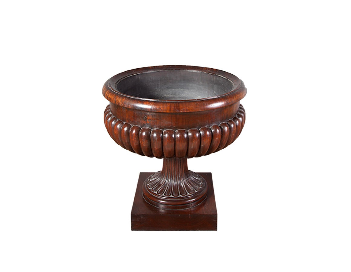 A George IV carved mahogany wine cooler attributed to Gillows.

The circular moulded lipped edge above a lobed body with a lead lined interior, this rests on a ring turned moulded socle, on a square plinth.