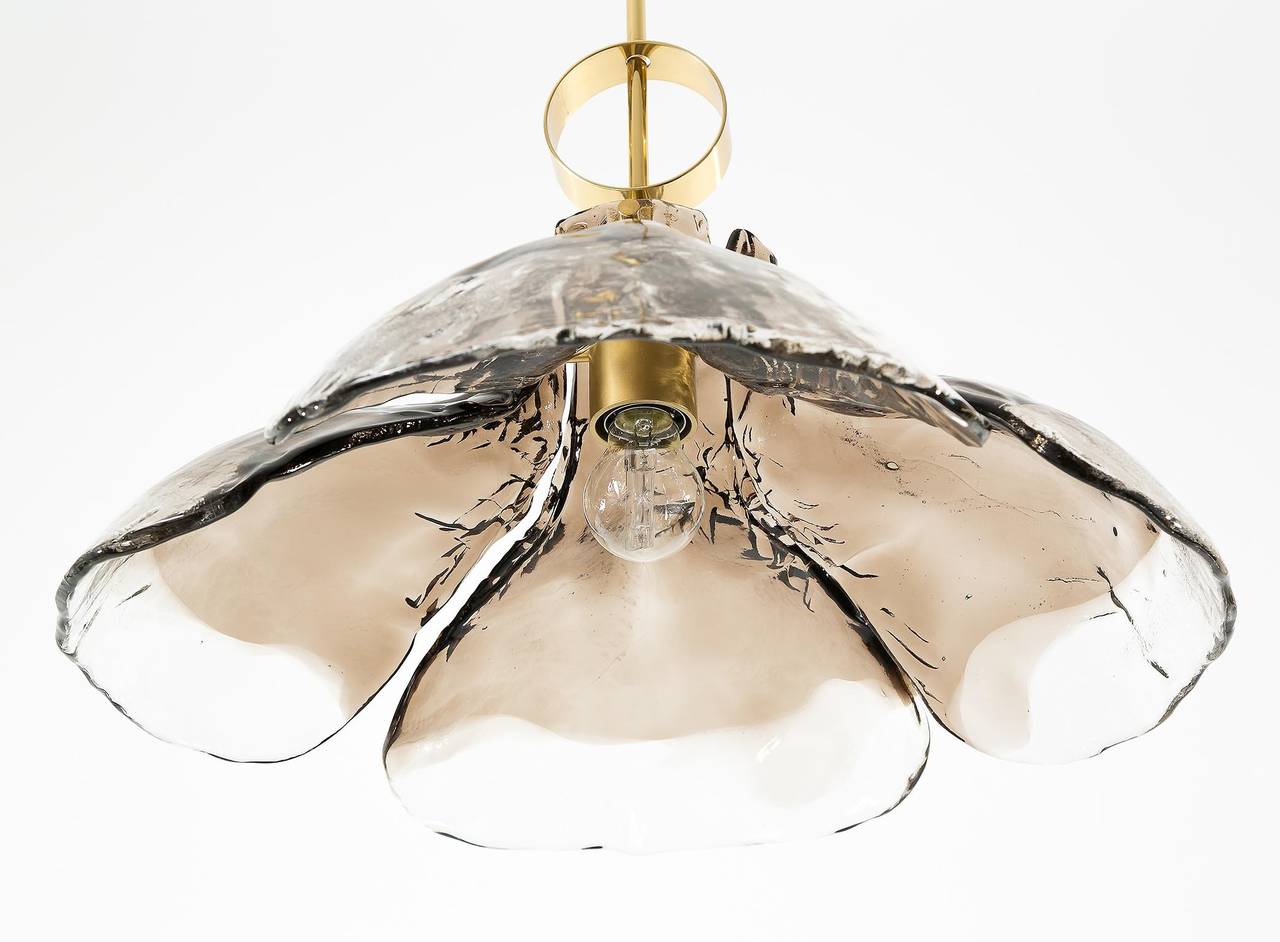 A beautiful pendant lamp by Kalmar, manufactured in Mid-Century, circa 1970 (late 1960s or early 1970s). 
Four hand blown brown smoke Murano glasses are mounted on a brass fixture which holds one socket for medium base Edison LEDs or bulbs.
Marked