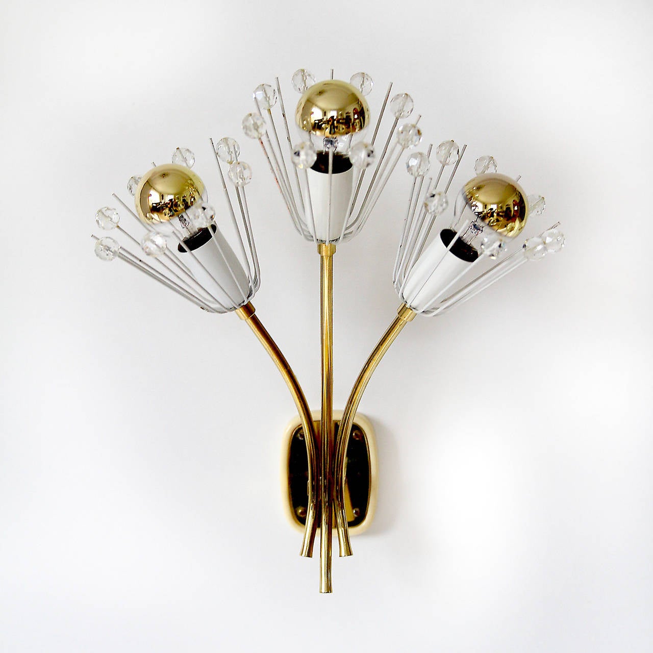 A charming Viennese pair of wall lights in the form of bunches of flowers by Emil Stejnar for Rupert Nikoll, Vienna Austria, manufactured in midcentury, circa 1950. 
The pieces are made of brass, white painted metal and handcut crystal glass. They