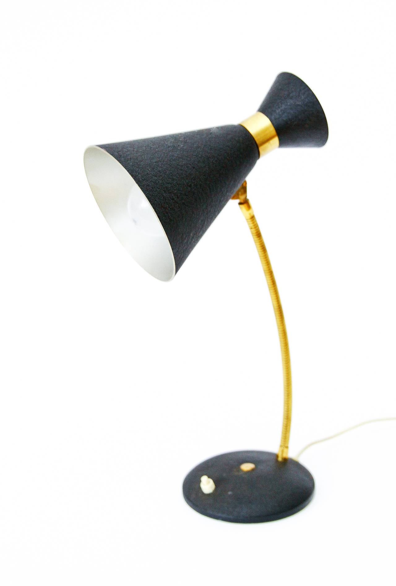 A table / desk light in the style of Stilnovo, Italy, manufactured in Mid-Century, circa 1950. It is made of brass and black lacquered metal. The shaft is flexible and can be turned into any direction.