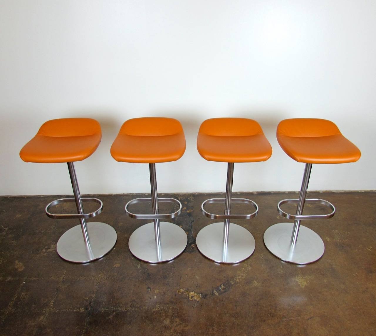 Set of four orange leather, white plastic, and matte polished aluminum Turtle bar stools by PearsonLloyd for Walter Knoll.

Stationary height, swivel bases.