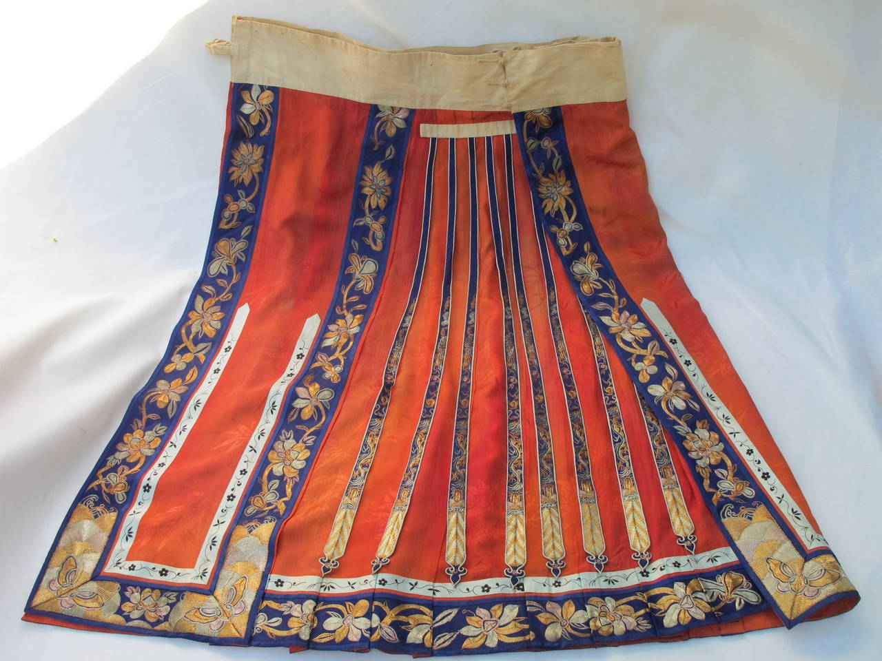 Heavily embroidered wedding skirt and over skirt, two-piece coral silk damask skirt with navy silk satin bands having couched gold and silver metallic floral embroidery. Wide linen waistband having floral embroidered silk streamers in various hues