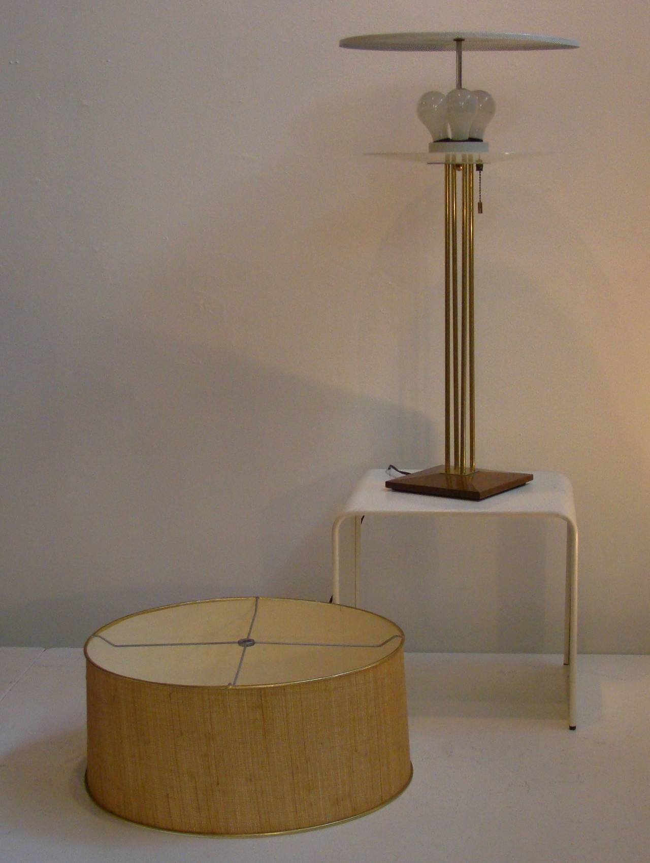 Beautiful and early table lamp by Gerald Thurston for Lightolier.  This lamp sits on a 4 prong brass and wood base and has the original grass cloth shade.  Both diffusers are present as well as the original pull chain.   C. 1950s