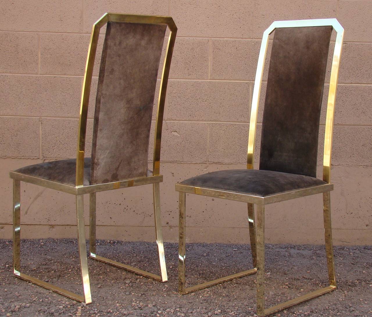 Stunning set of six high back brass dining or side chairs. These chairs are a polished gold tone chrome steel with split cowhide upholstered seats. These were purchased from Roche Bobois in the 1980s and came from the original owners.