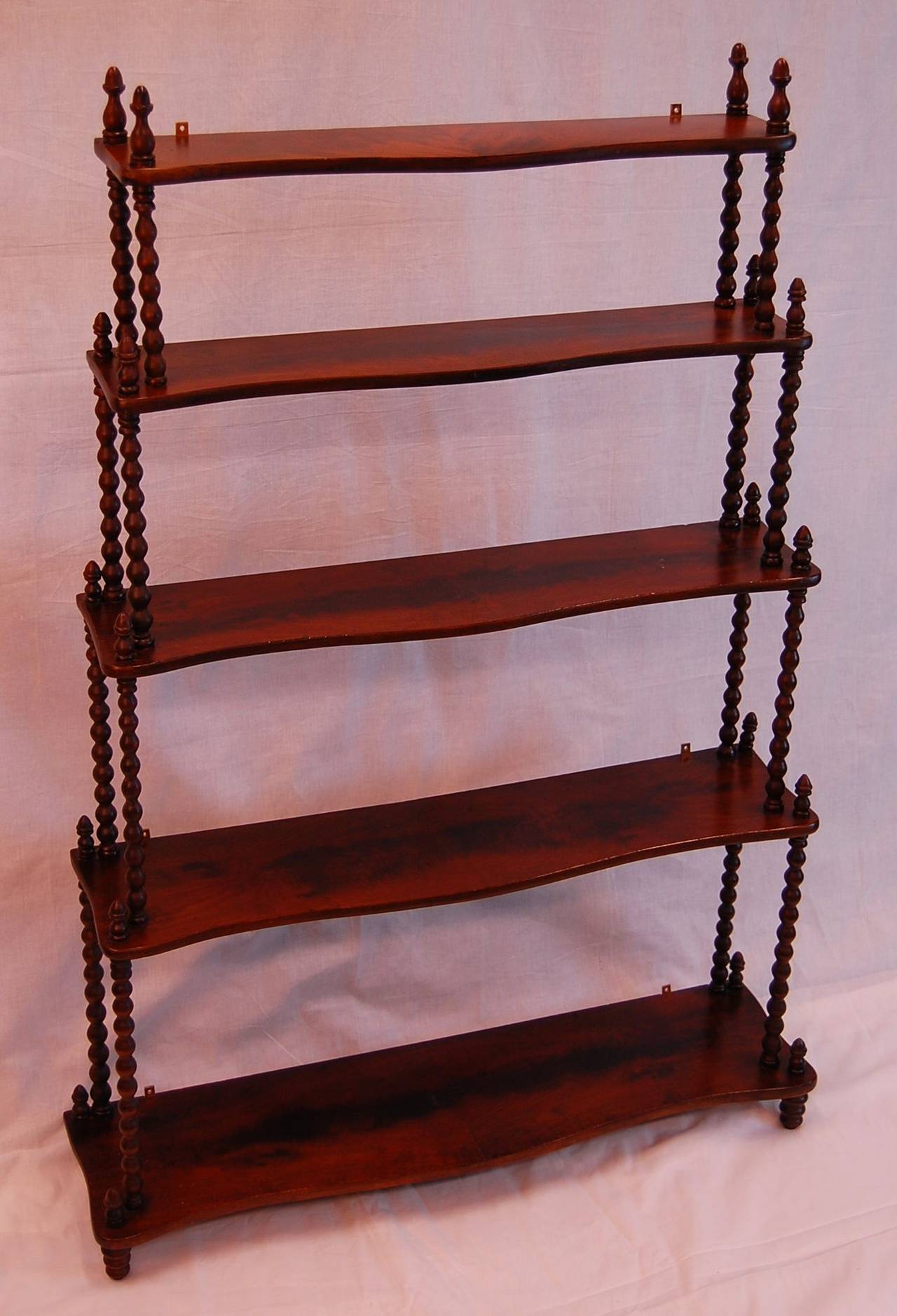 Mahogany 5 tier wall mounted shelf in excellent condition. The depth of each shelf at center is: 5.5"; 6.25; 7.25; 8.25; 9.25. Excellent condition with mounting brackets attached.