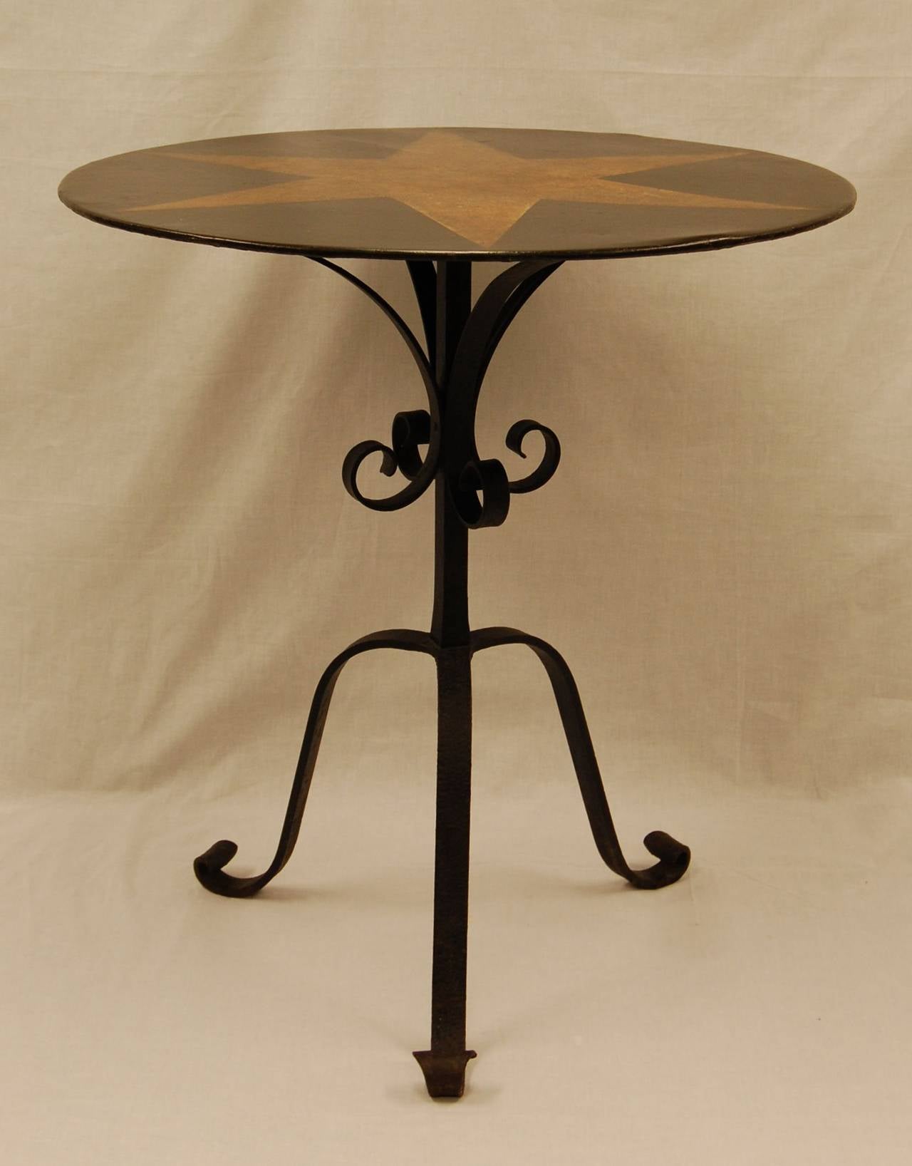Wrought iron table base with circular painted metal top, turn of the century. Original paint in excellent condition.