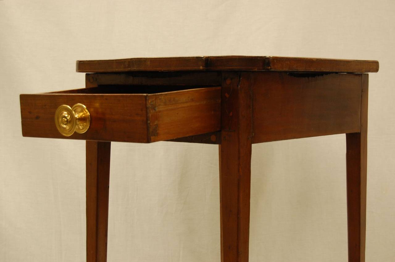 An early 19th century work or side table with one drawer and fancy brass knob in excellent condition. Likely Walnut, in a dark finish. Tramp style inlay on the front of the drawer box. The brass knob is not original.