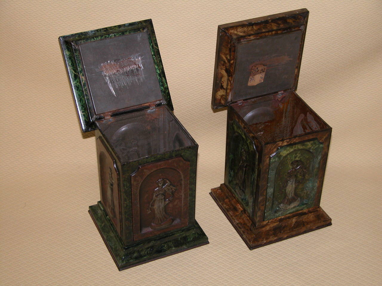 An early pair (1909) of Huntley and Palmers collectable biscuit tins in the shape of architectural pedestals, with four female figures in classical costume in the niches on each side. Faux decorated in green and rust to replicate marble. Hinged